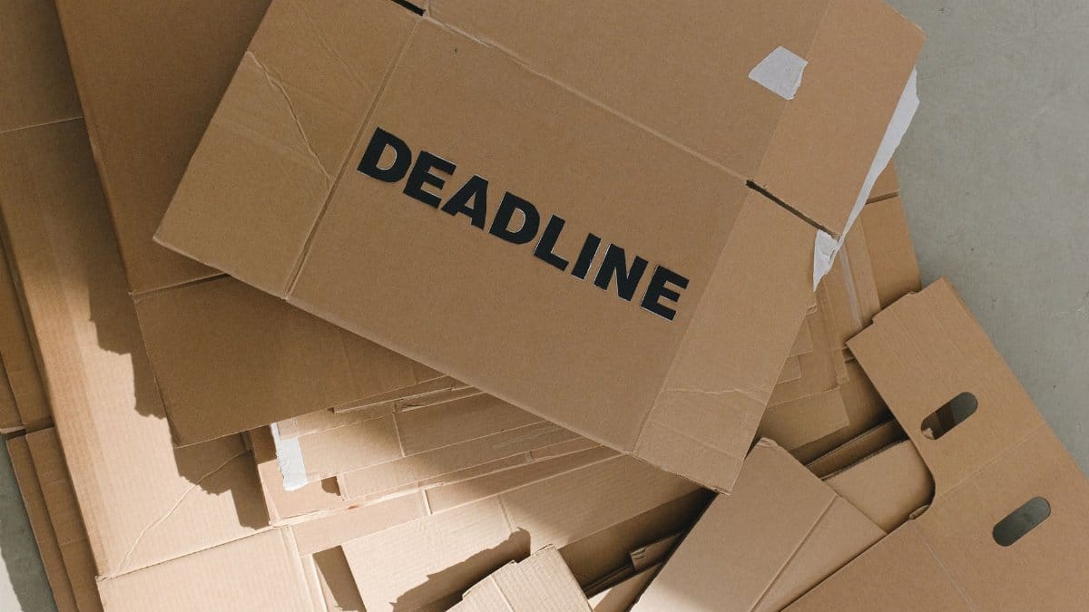 Pile of cardboard boxes with bold 'Deadline' label indoors, emphasizing urgency.