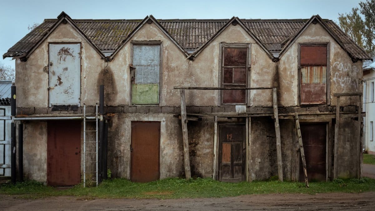 A derelict and dilapidated building with broken doors and wooden structures showcasing decay.