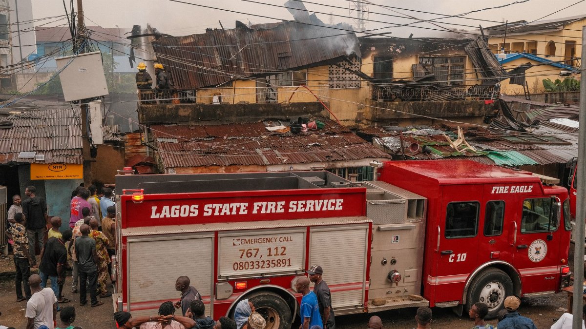 Firefighters respond to a blaze in Lagos, Nigeria, with a red fire truck and local residents observing.