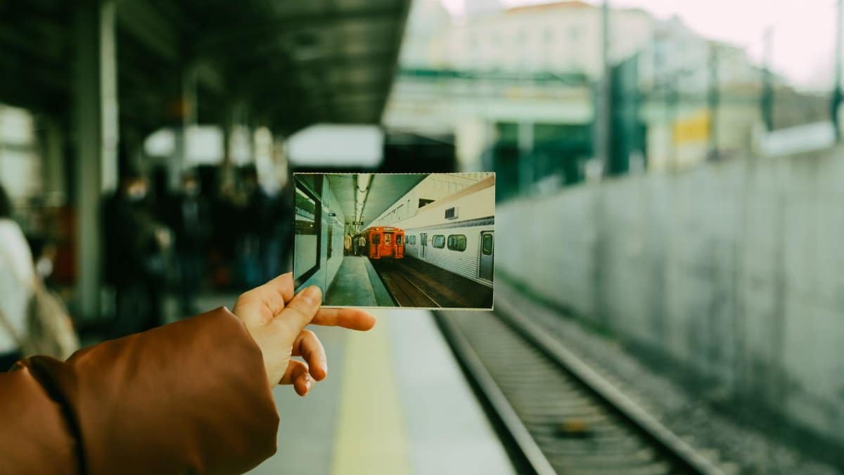 A person holds a photograph of a train at a railway platform in İstanbul, Türkiye.