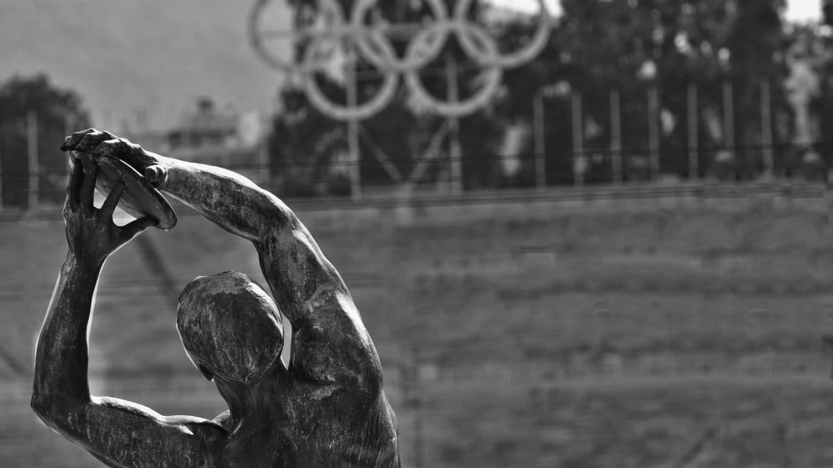 Black and white photo of a statue with Olympic rings in Panathenaic Stadium, Athens.