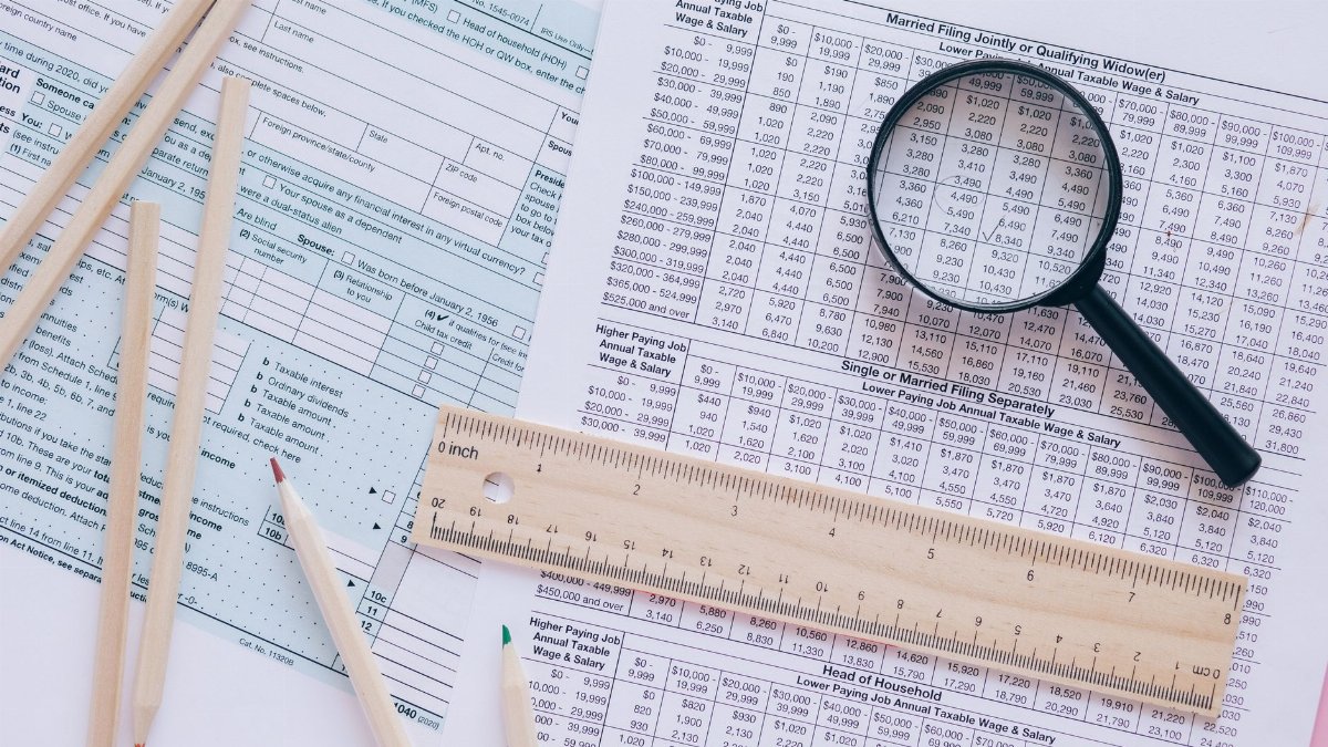 A high angle view showing IRS tax forms with pencils, ruler, and magnifying glass for financial planning.