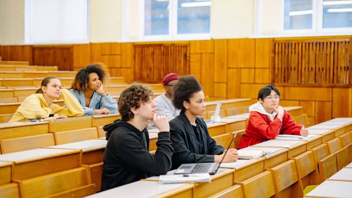 Students of various backgrounds attentively listening in a university lecture hall.