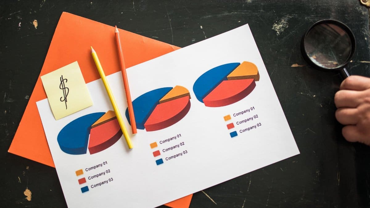 Colorful pie charts on paper with office supplies on a desk, illustrating financial data analysis.