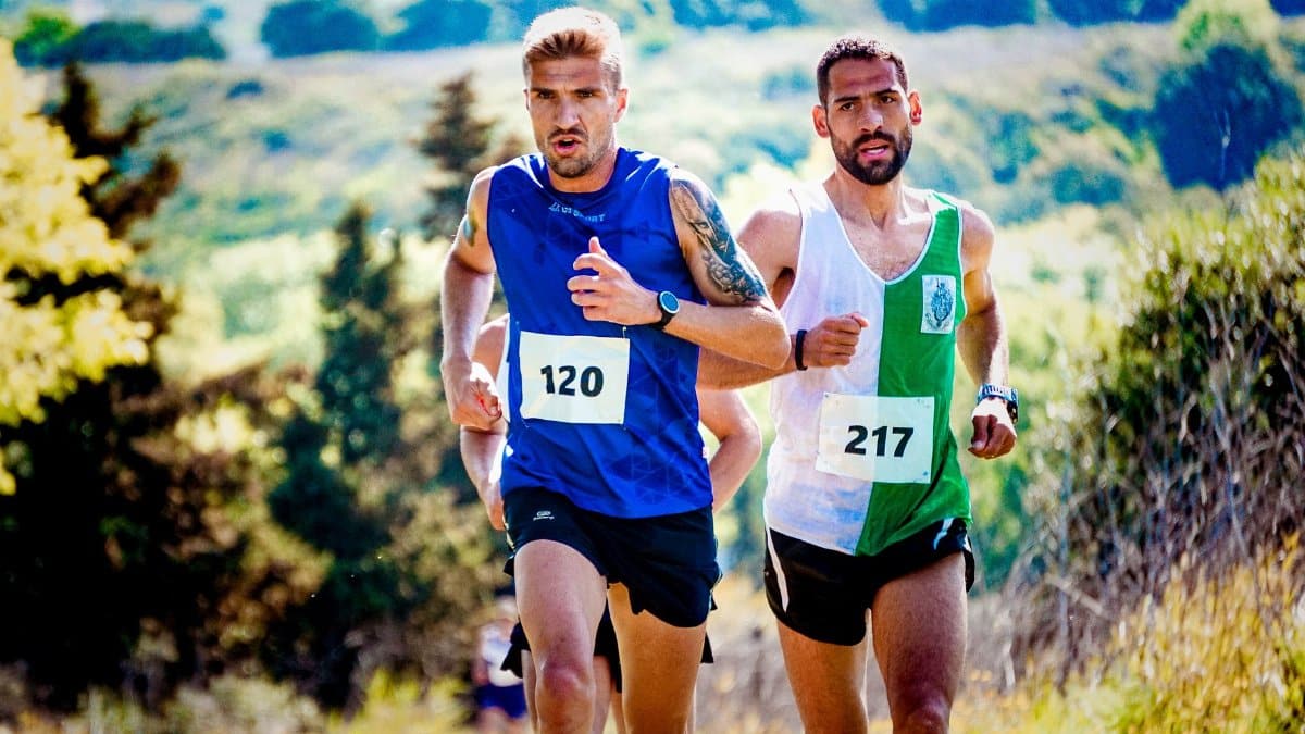 Two male runners with numbered bibs compete in an outdoor race, showcasing determination and endurance.