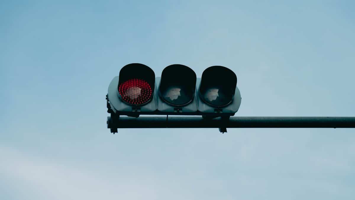 A close-up of a red traffic light set against a clear blue sky, conveying safety and caution.