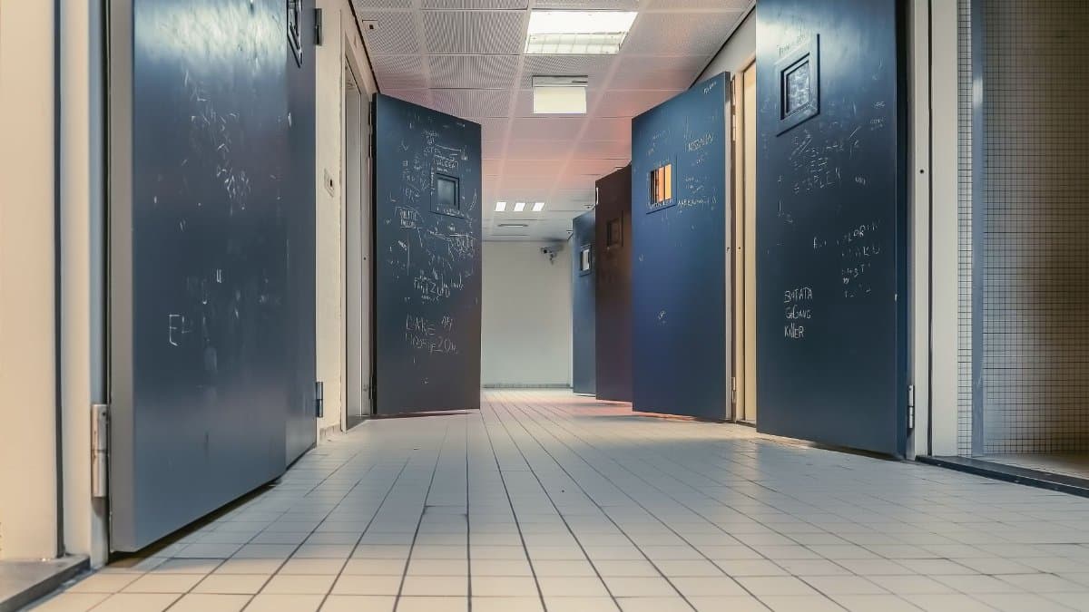 Low angle view of a modern hallway with open blue doors and white tiled flooring, creating a clean and tranquil environment.