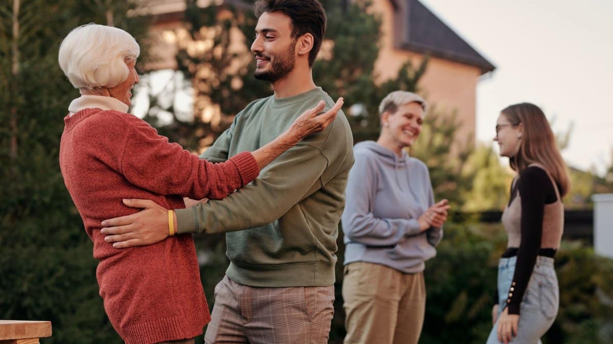 A joyful family gathering outdoors with diverse generations embracing and smiling.