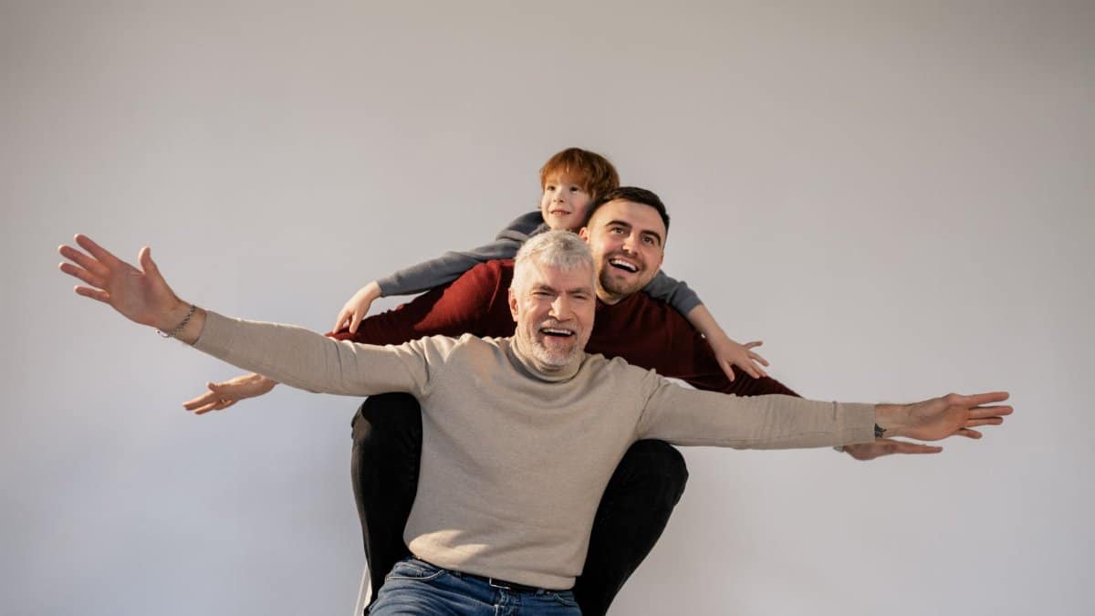 Three generations of a family joyfully bonding indoors with playful expressions and togetherness.