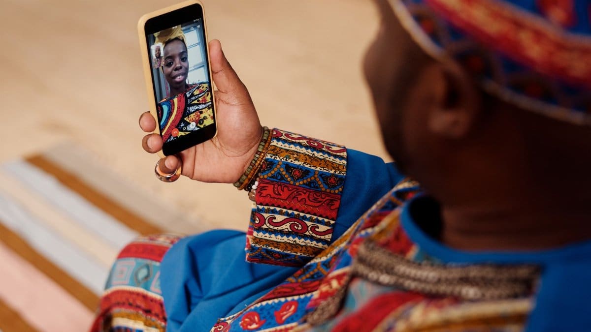 A person wearing colorful attire engages in a video call, celebrating cultural connection and technology.