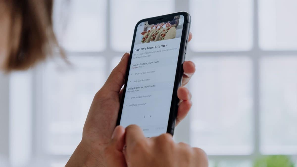 Close-up of hands using a smartphone to order food online through an app, showcasing modern technology.