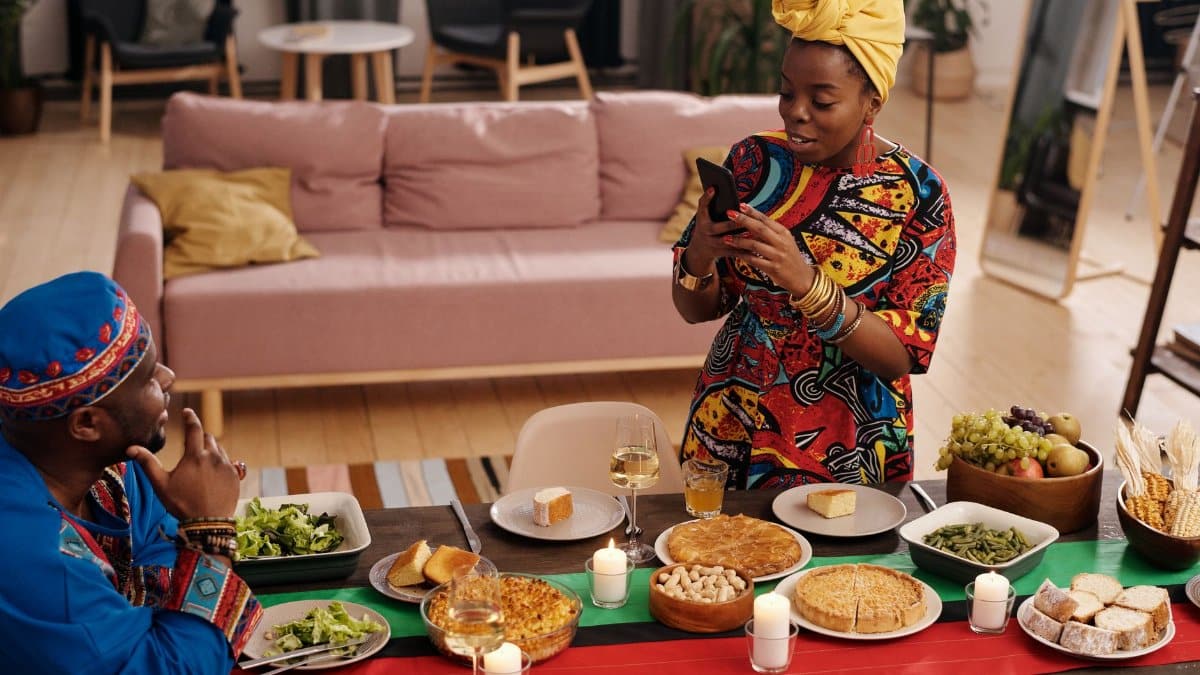 A joyful family celebrating Kwanzaa with traditional food and colorful attire indoors.