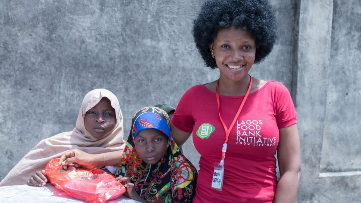 Volunteers and beneficiaries smiling at Lagos Food Bank Initiative, showcasing community support.