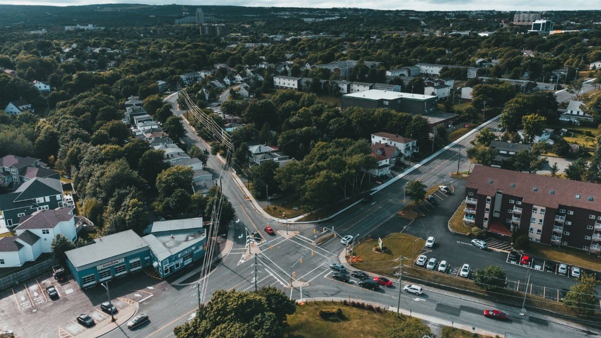 A vibrant aerial view of an urban area featuring an intersection, buildings, and lush greenery.