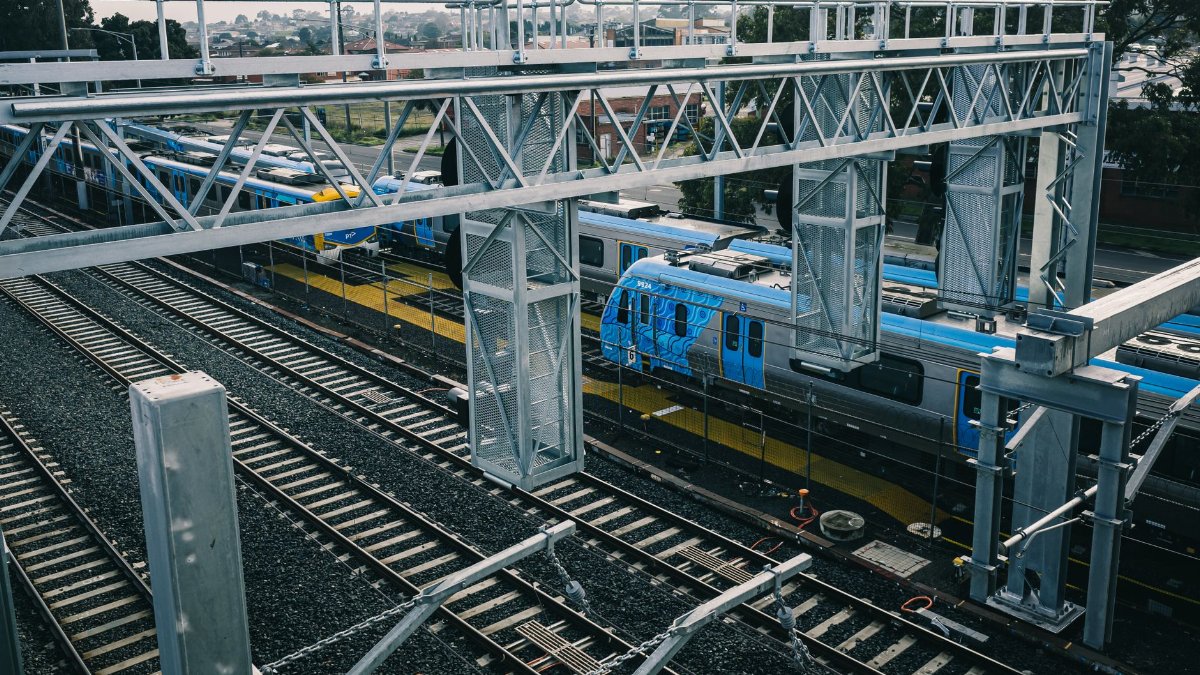 Aerial view of modern railways and blue train in urban setting, showcasing transportation infrastructure.