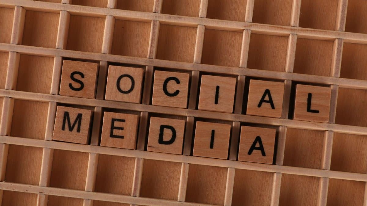 Close-up of wooden letter blocks spelling 'Social Media' on a wooden grid.