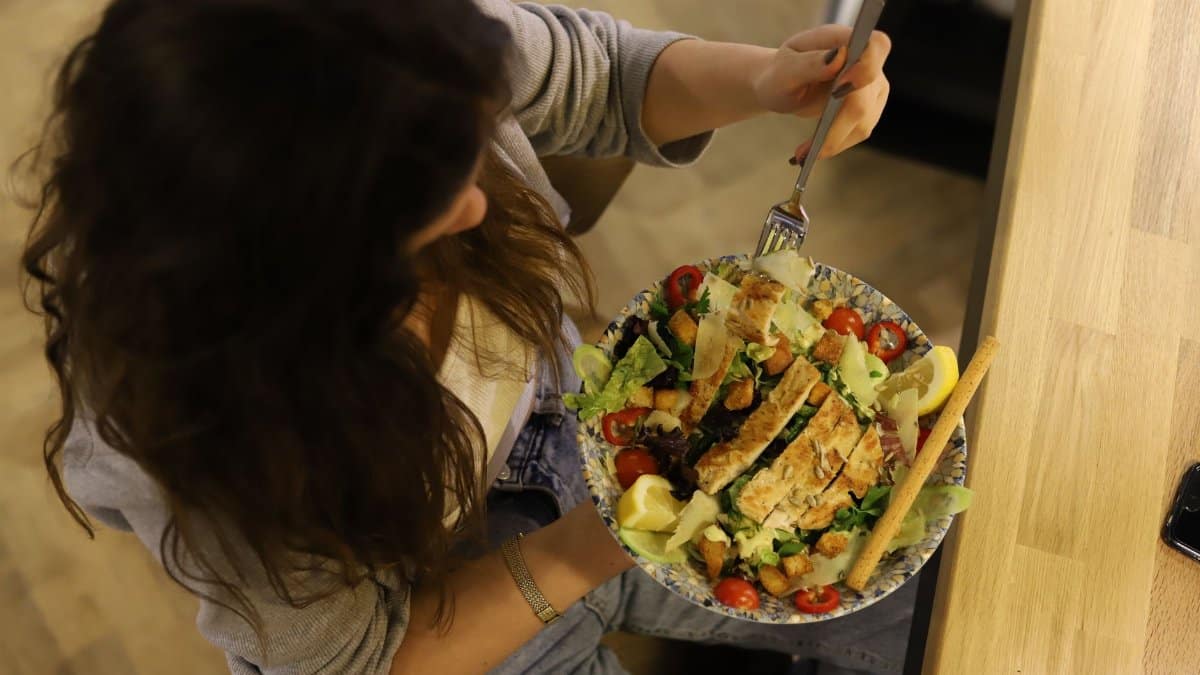Overhead view of a woman eating a chicken salad balancing health with deliciousness.