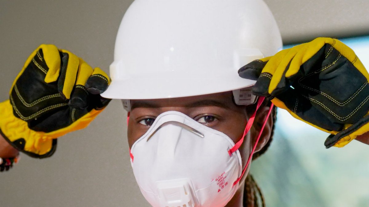 Construction worker wearing hardhat, N95 mask, and gloves for safety.