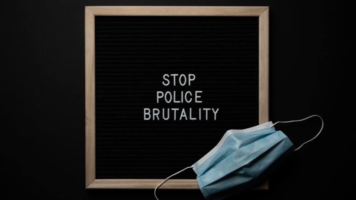 Top view composition of framed black image with white text Stop Police Brutality near medical protective mask