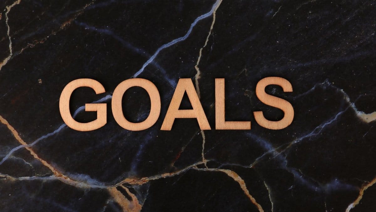 Wooden letters spelling 'GOALS' on a dark marble surface, symbolizing ambition and achievement.