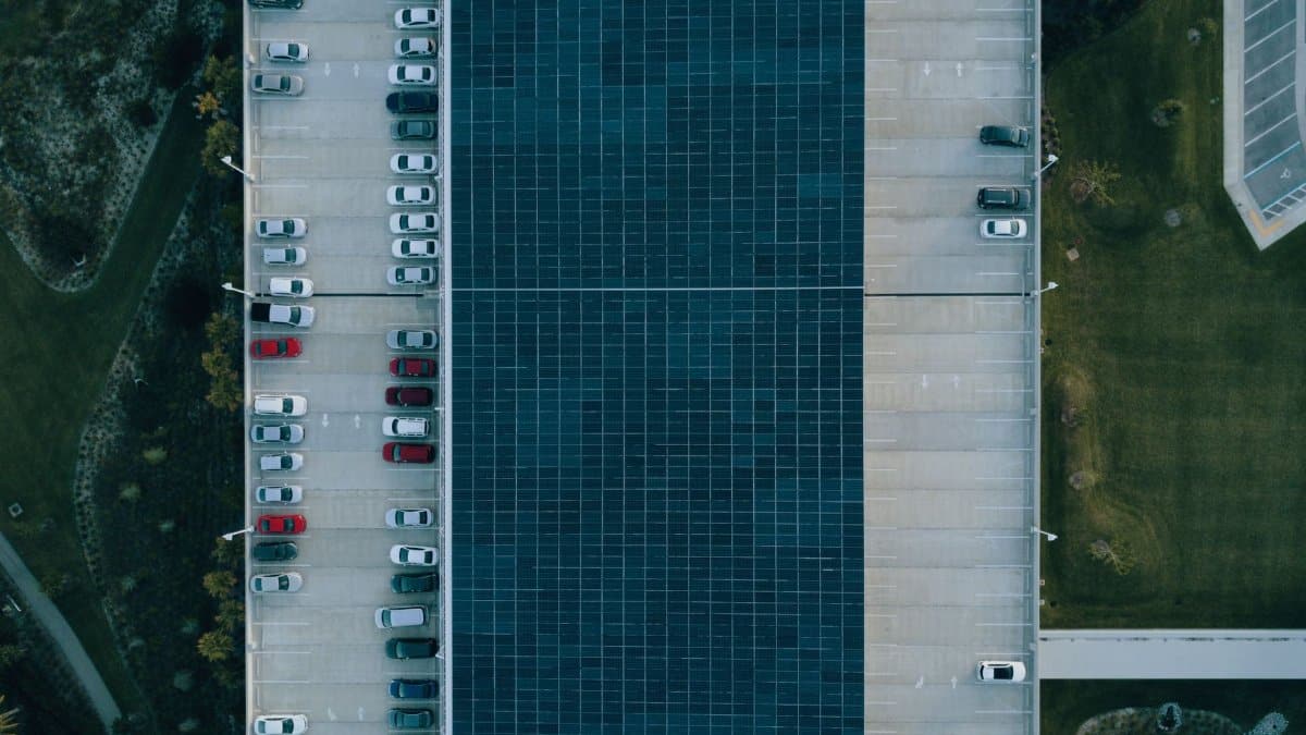 Top view of a parking lot with cars and solar panels, showcasing urban sustainability.
