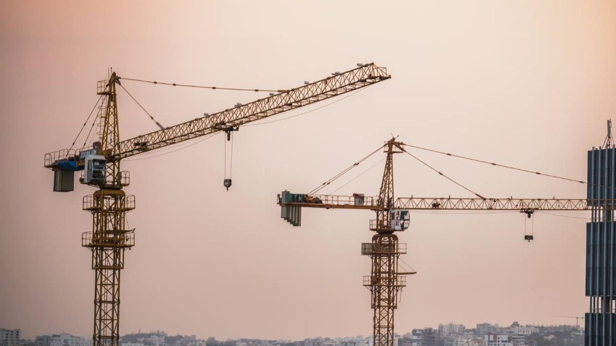 Skyline view of an urban construction site with prominent tower cranes at dusk.