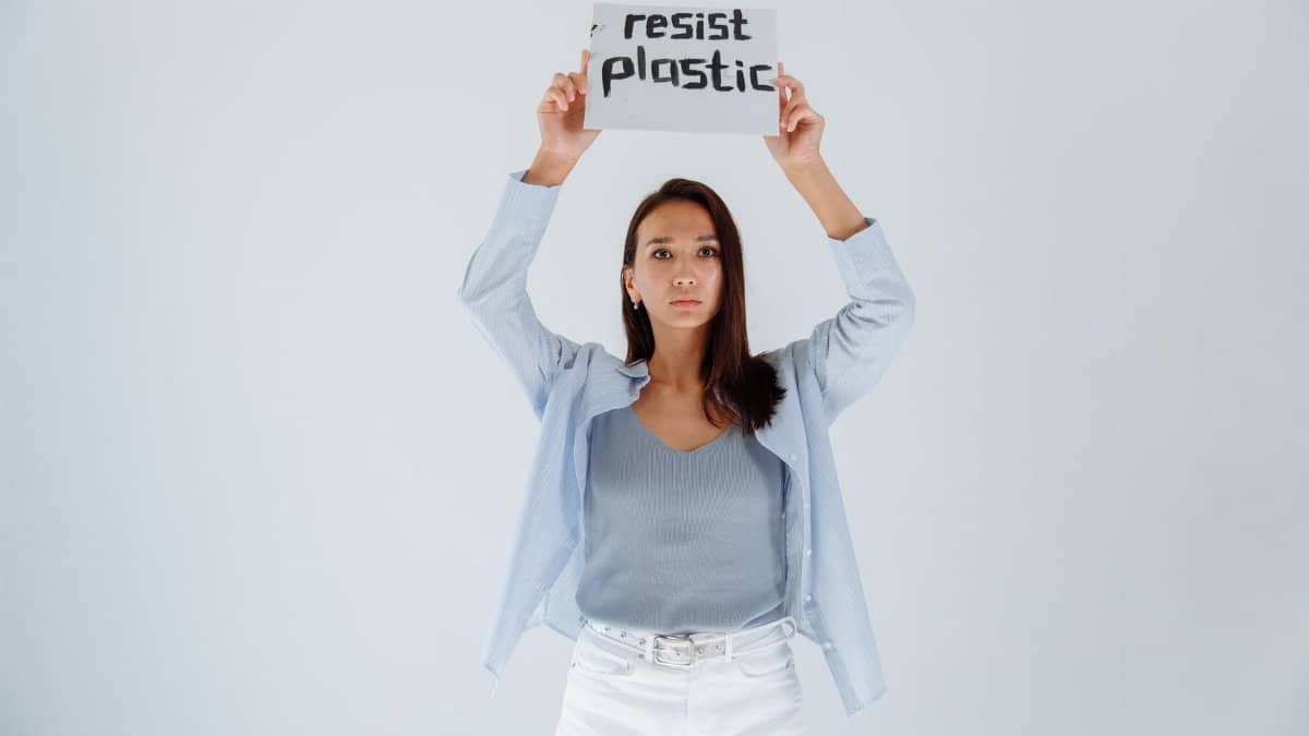 Portrait of a young woman holding a sign advocating resistance to plastic pollution, symbolizing activism and environmental awareness.
