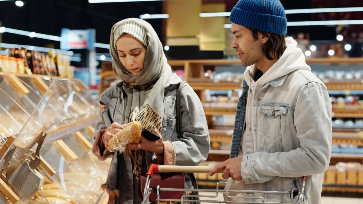 Couple selecting bread in a modern supermarket while grocery shopping together.