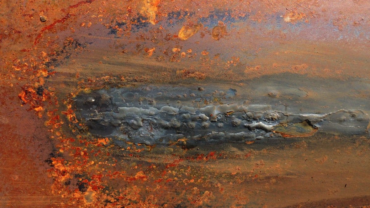 Abstract close-up of a rusty metal surface with vibrant textures and colors.