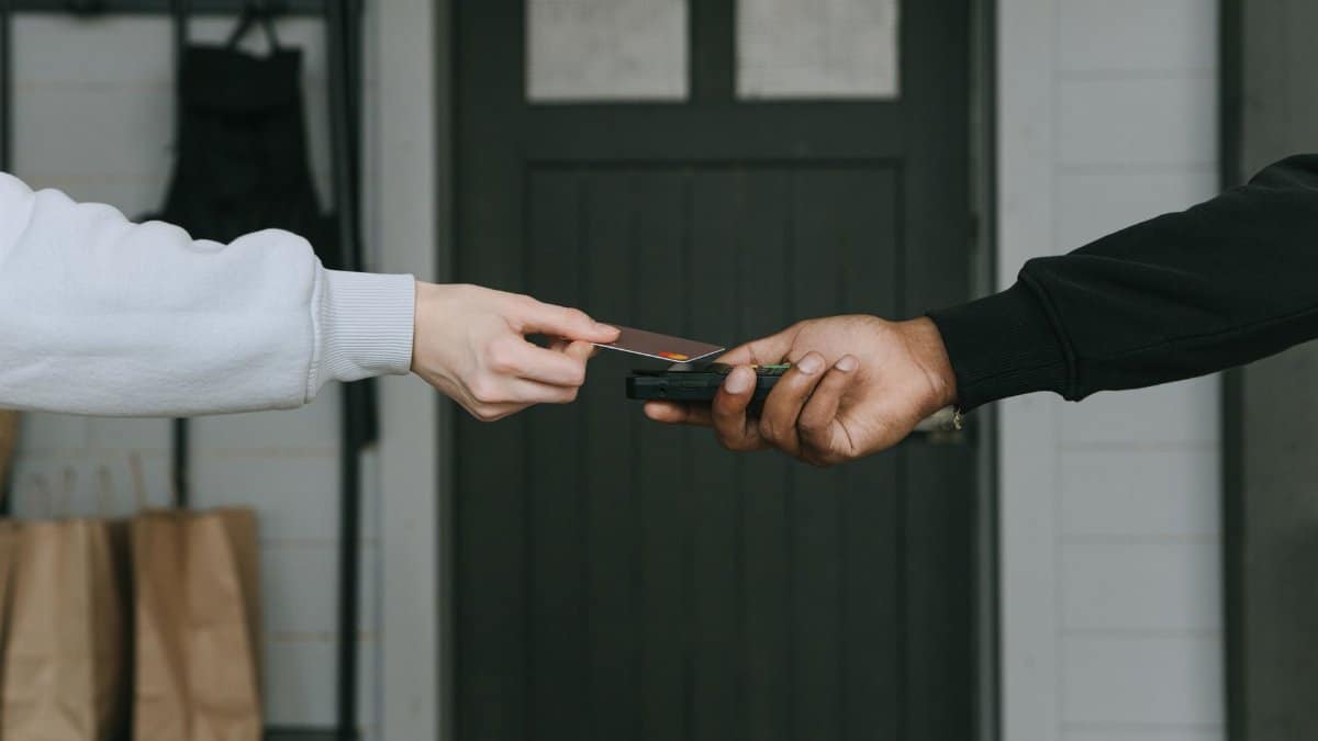 Close-up of hands making a contactless card payment indoors, highlighting cashless transaction technology.