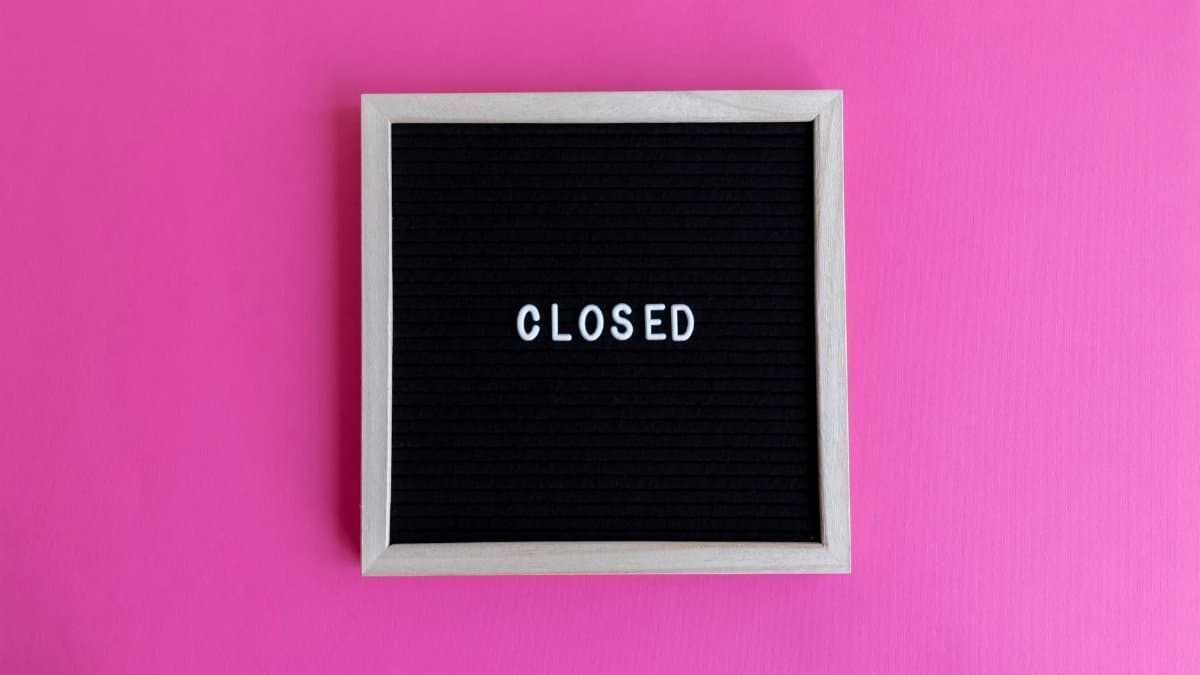 A minimalist blackboard sign with 'CLOSED' text on a vibrant pink background.