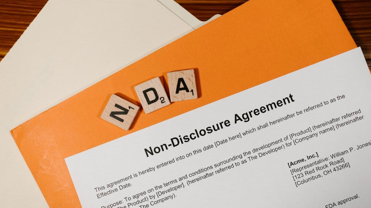 Top view of a Non-Disclosure Agreement with NDA in Scrabble tiles, emphasizing confidentiality.