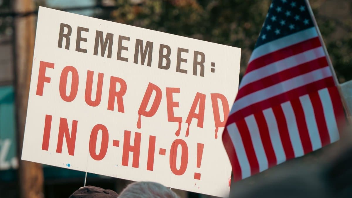 Sign commemorating the Kent State incident with American flag in a peaceful protest setting.