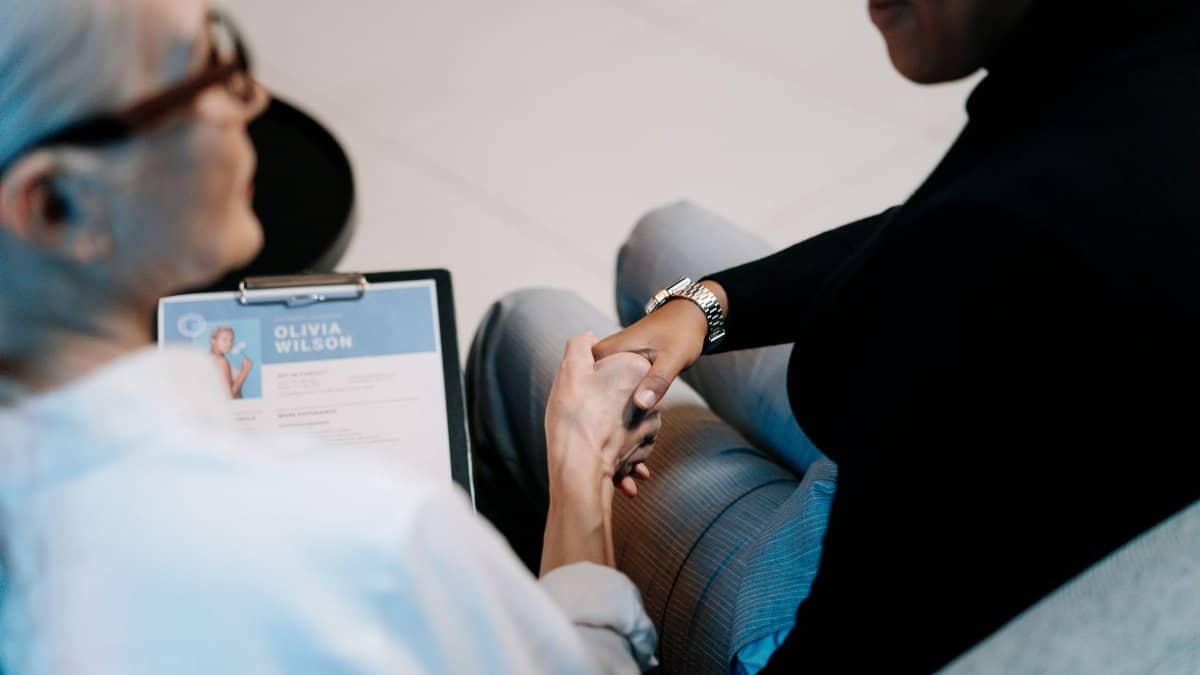 Two professional women having a handshake in an office setting, focusing on recruitment and connection.