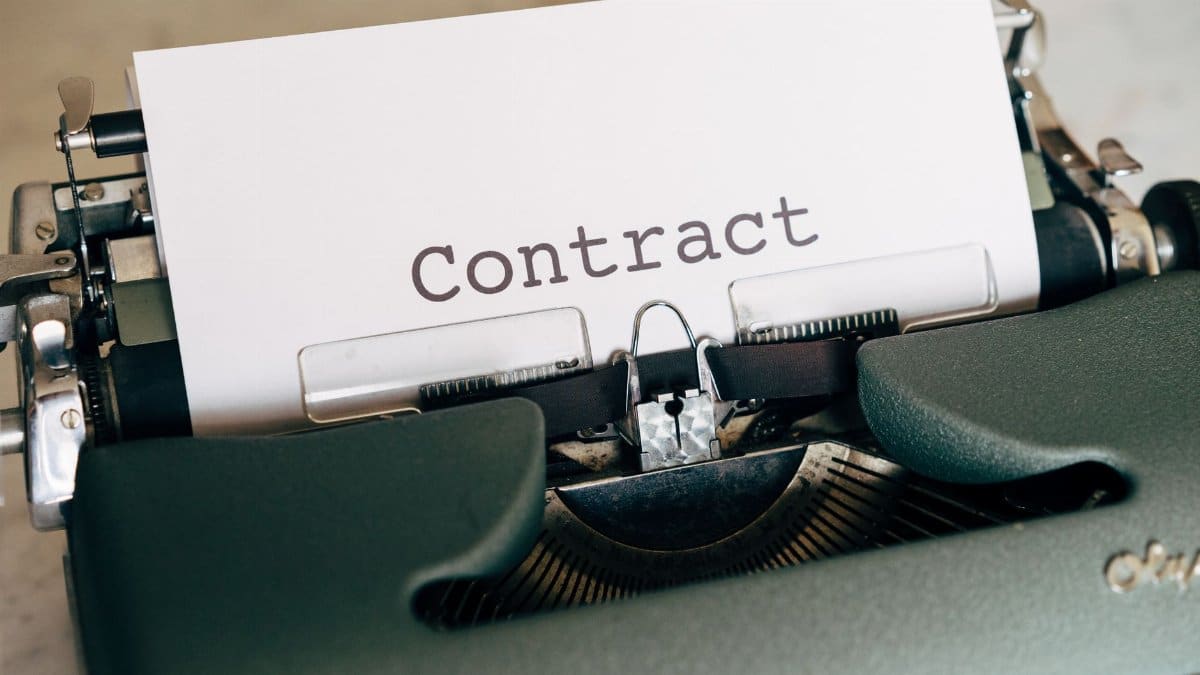 A close-up of a vintage typewriter with a typed contract page.