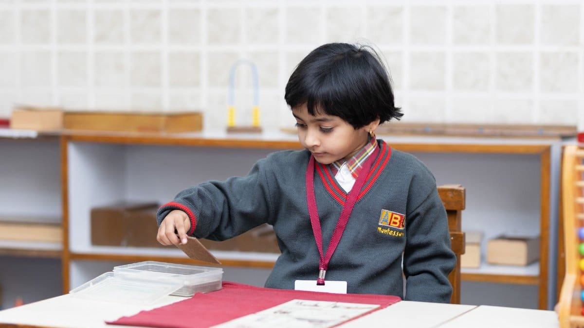 Child engaged in learning activity at a Montessori school, developing fine motor skills.