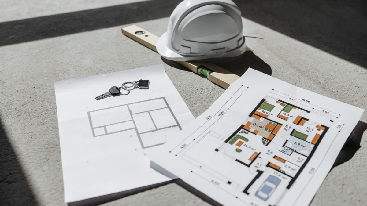 Architectural floor plans with helmet and keys on sunlit floor, perfect for real estate or construction themes.