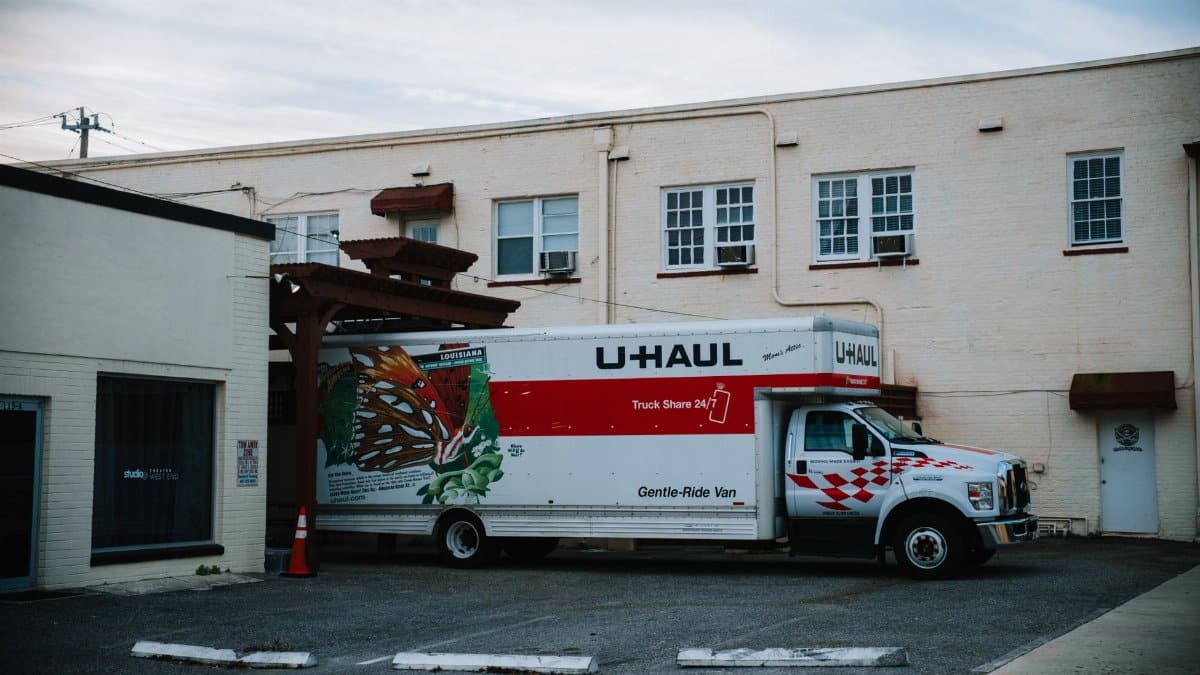 A U-Haul moving truck parked in front of a beige warehouse building.