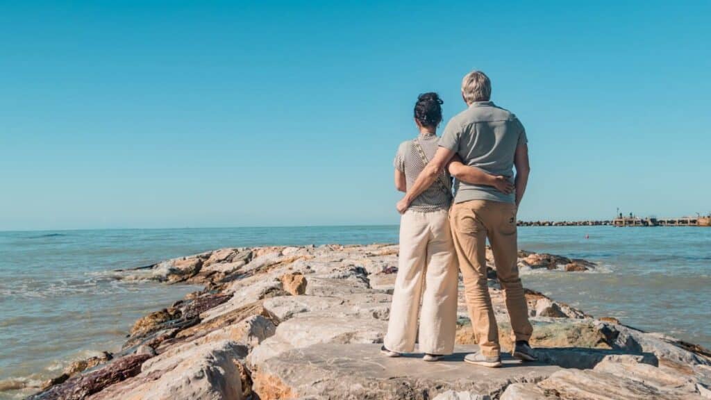 Romantic couple embracing, enjoying seaside view on rocky beach in Vada, Tuscany.