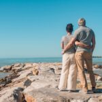 Romantic couple embracing, enjoying seaside view on rocky beach in Vada, Tuscany.