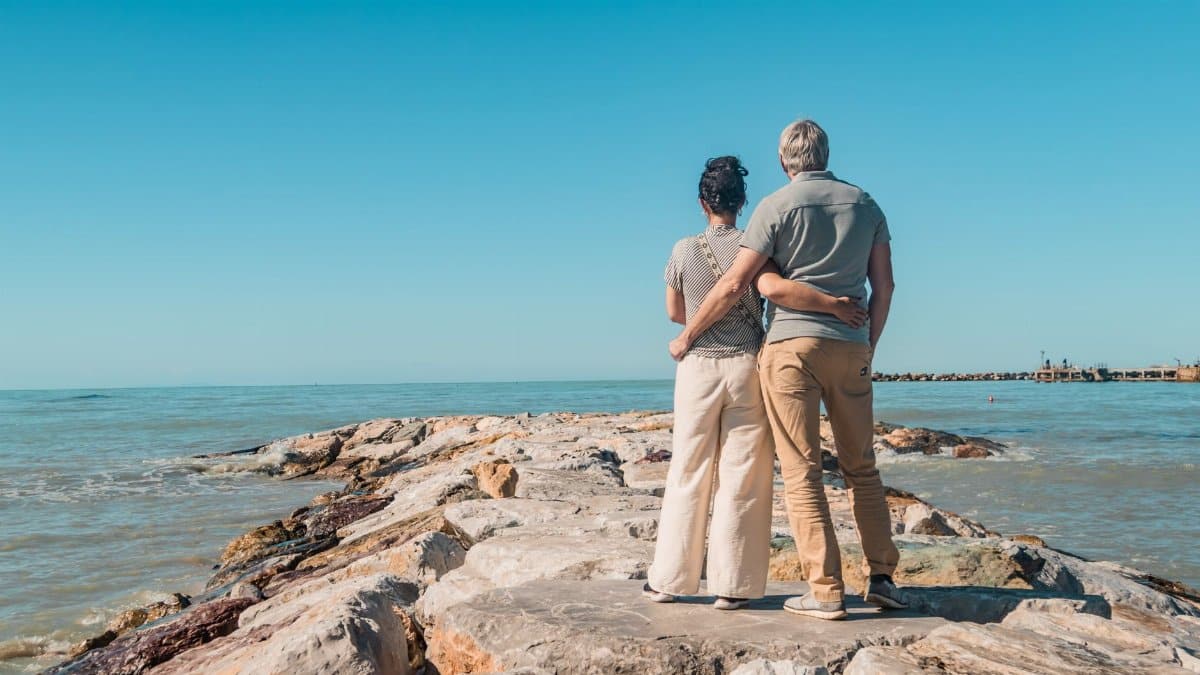 Romantic couple embracing, enjoying seaside view on rocky beach in Vada, Tuscany.