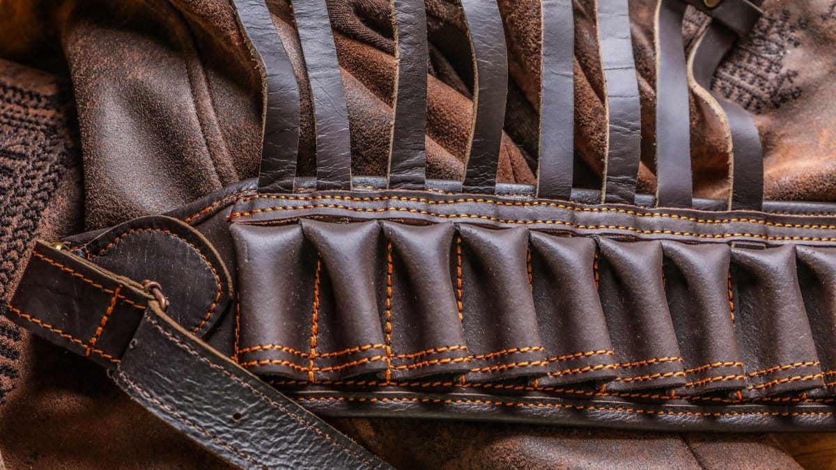 Detailed closeup of a brown leather ammo belt on a textured leather jacket.