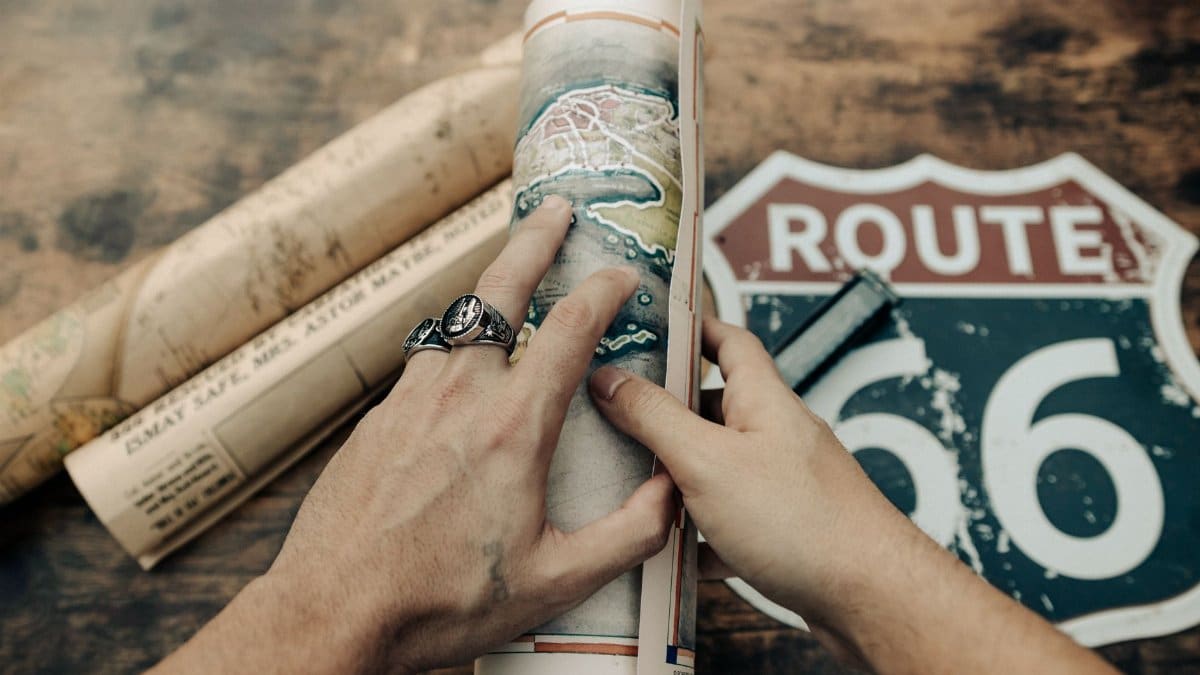 Two hands holding vintage maps of Route 66 on a wooden table. Perfect for travel and history themes.