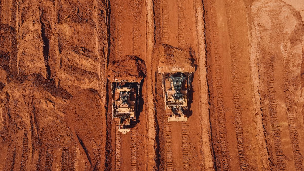 Aerial shot of two tractors excavating red earth, showcasing construction and mining machinery in Brazil.