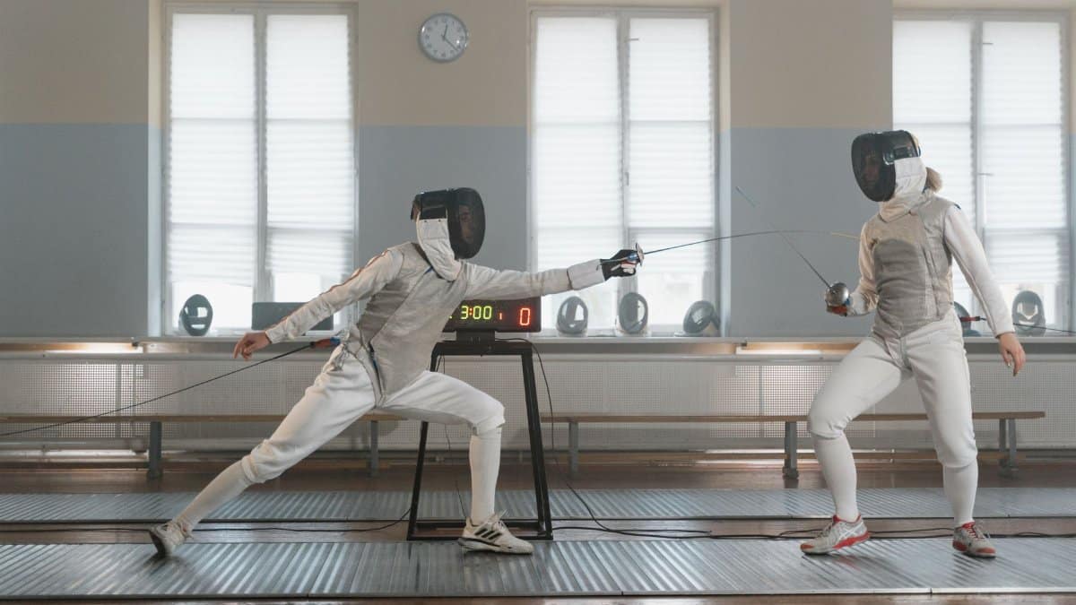 Two fencers practicing in an indoor gym, capturing the action and precision of fencing.
