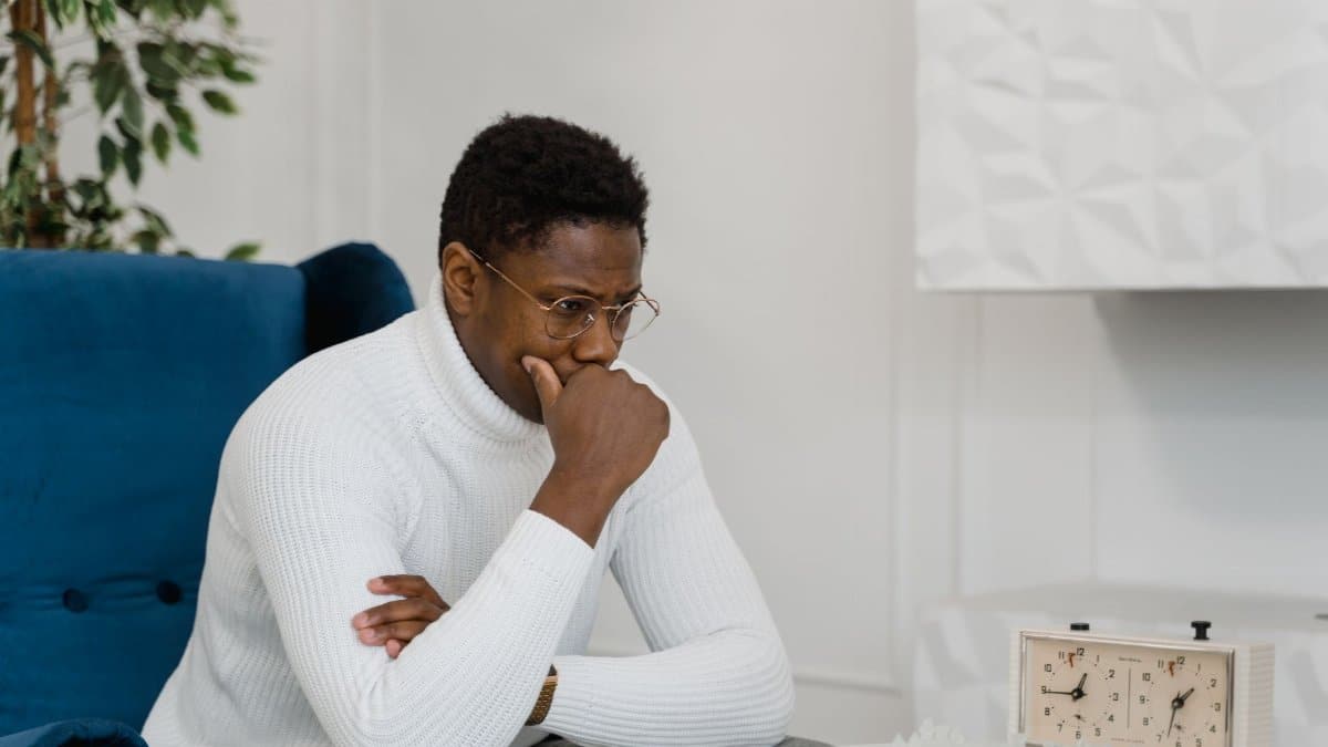 Thoughtful man in white sweater playing chess indoors, emphasizing strategy and focus.