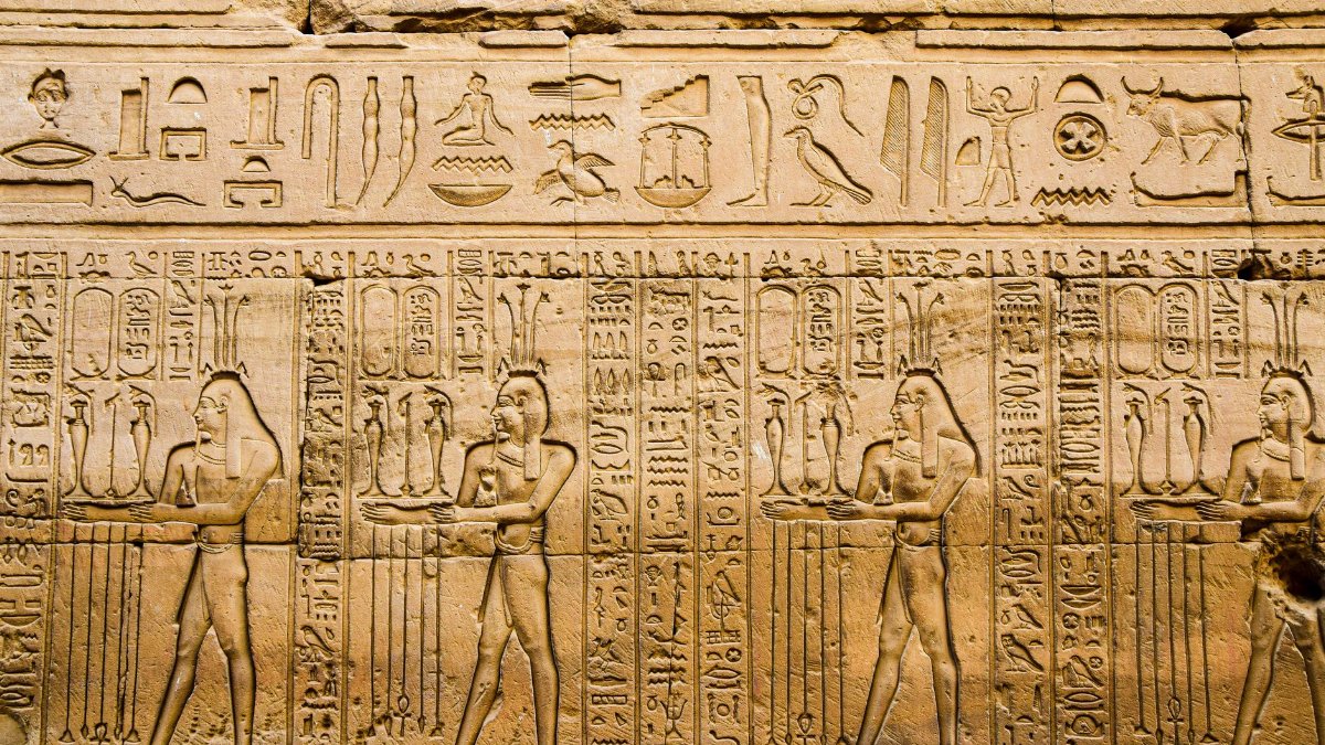 Detailed hieroglyphics and carvings on a wall in Luxor, Egypt, showcasing ancient history.