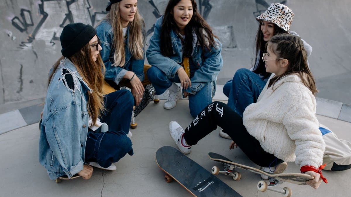 Group of diverse teenagers hanging out at a skatepark, chatting and enjoying leisure time.
