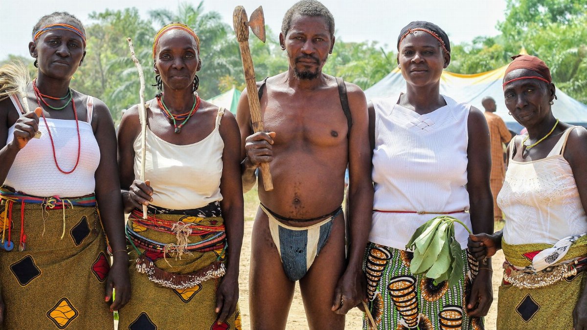 A group of African adults in traditional tribal clothing posing outdoors, showcasing cultural heritage.