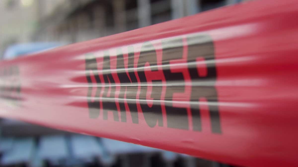 Focused close-up of red danger barricade tape at a construction site.